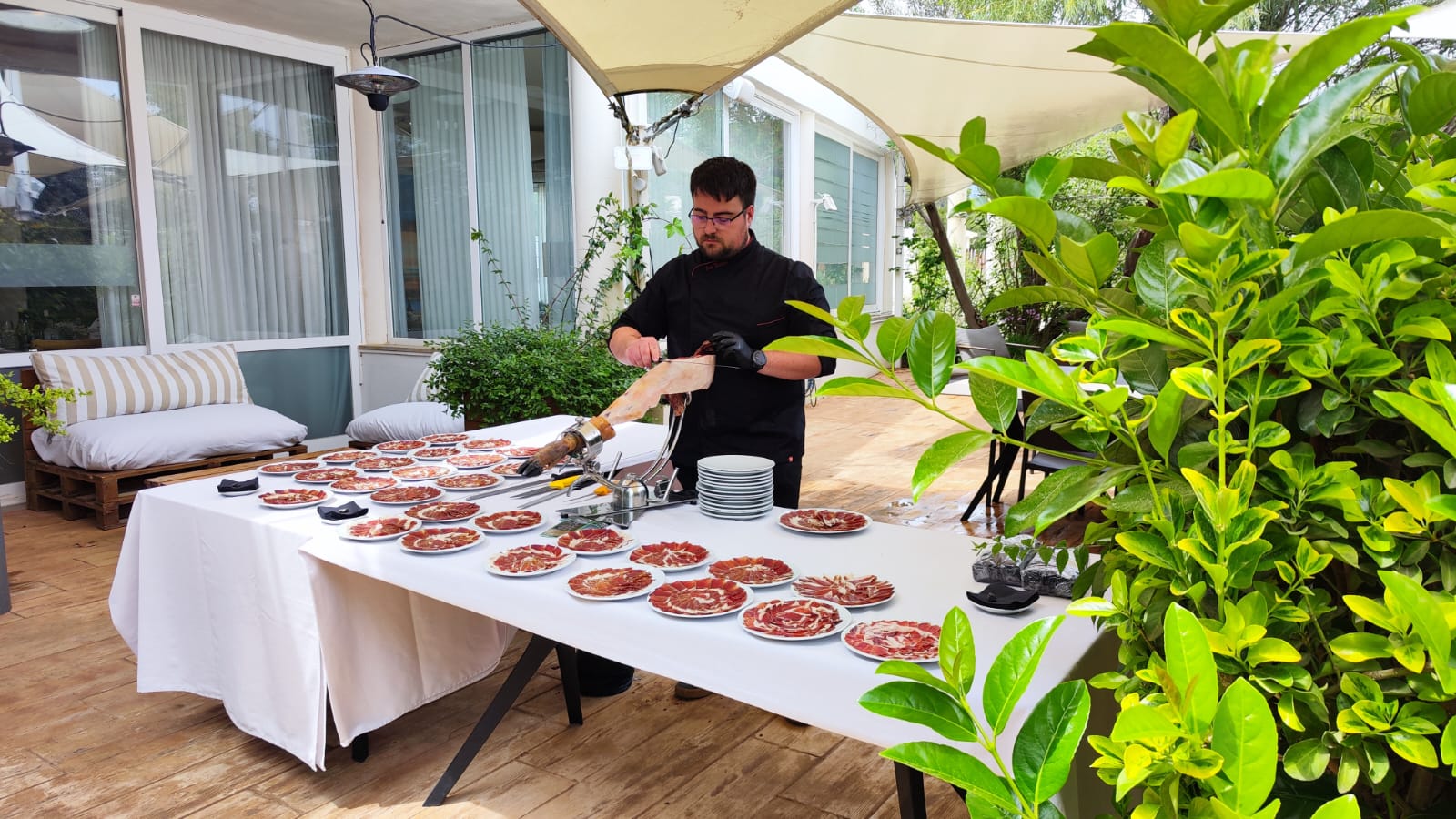 Ivan Montero cortando jamón ibérico en evento al aire libre en Tortosa con múltiples platos servidos